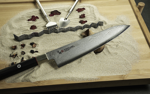Japoński nóż kucharza Gyuto Mcusta Zanmai Splash Damascus na tle piasku