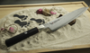 Nóż Mcusta Zanmai Gyuto 24 cm z serii Splash Damascus na piasku.