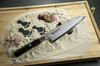 Nóż Santoku Mcusta Zanmai Splash Damascus na piasku, tło dekoracyjne.