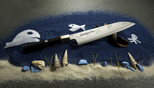 Nóż Santoku Mcusta Zanmai Splash Damascus na tle morskiej kompozycji z muszlami