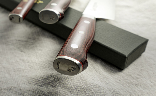 33-warstwowy nóż kucharza Mcusta Zanmai Gyuto Classic Pro Flame, 21 cm, na tle pudełka.