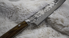 Ręcznie kuty nóż Gyuto 21 cm Takeshi Saji na miękkim tle.