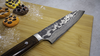 Ręcznie kuty nóż Santoku Takeshi Saji na desce z kolorowymi ciasteczkami
