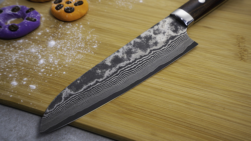 Mistrzowski nóż Santoku Takeshi Saji VG-10 na desce z kolorowymi ciastkami