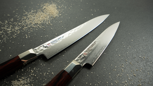 Damasceński nóż Nakiri Mcusta Zanmai Supreme Hammered, 16,5 cm, na tle szarego blatu.