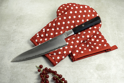 Nóż kuchenny Miyabi 4000 FC Gyuto na czerwonej rękawicy kuchennej.