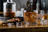 Szklanki Bar Premium No.2 Zwiesel GLAS z bursztynowym napojem i lodem na drewnianym stole.
