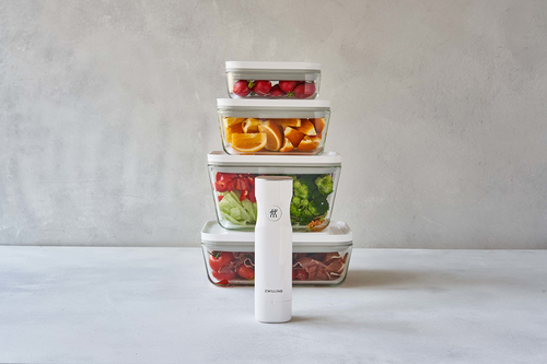 Szklane pojemniki Fresh & Save Zwilling z warzywami i owocami na tle jasnej ściany.
