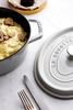 Głęboka patelnia żeliwna Staub White Truffle z pokrywą, wypełniona puree i truflami.