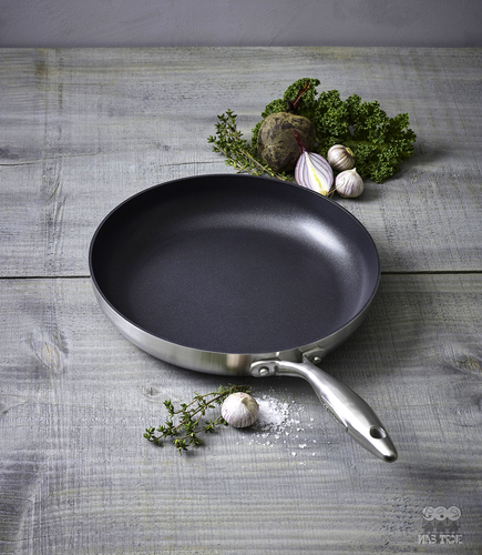 Scanpan CTX tytanowo-ceramiczna patelnia Ø 20 cm na drewnianym blacie z ziołami.