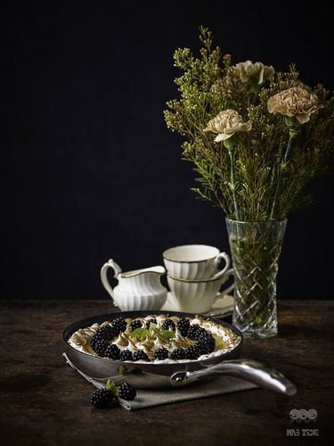 Scanpan HaptIQ tytanowo-ceramiczna patelnia z owocowym deserem, elegancka zastawa i kwiaty.