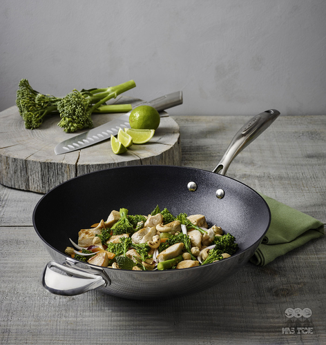 Wok HaptIQ Scanpan z powłoką Stratanium Plus pełen warzyw i kurczaka, obok nóż i limonka.