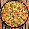 Żeliwna patelnia Skeppshult Original z zapiekanym pieczywem i ziołami na drewnianym stole.