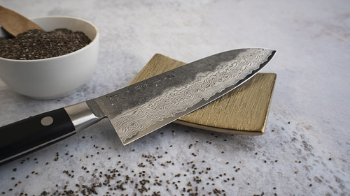 Japoński nóż Santoku Hatsukokoro Atelier Tomoo Matsumura na tle drewnianej deski.