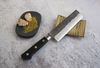 Nóż Nakiri Hatsukokoro Atelier Tomoo Matsumura na tle muszli.