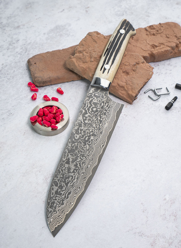 Santoku Takeshi Saji, 18 cm, damasceńska stal, WBB R2, na tle cegiełek i przypraw.