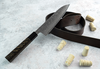 Nóż Santoku Sakai Takayuki Ginga na tle skórzanego paska i korków.