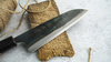 Japoński nóż Santoku Iron Kurouchi Sakai Takayuki na tle drewnianej deski