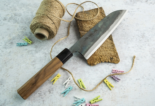 Japoński nóż Santoku Iron Kurouchi Sakai Takayuki na tle kuchennym