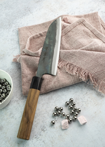 Japoński nóż Santoku Sakai Takayuki Iron Kurouchi na tle lnianej serwetki.