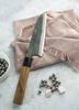 Japoński nóż Santoku Sakai Takayuki Iron Kurouchi na tle lnianej serwetki.
