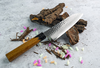 Japoński nóż Santoku Urushi Sakai Takayuki na tle drewnianych kawałków.