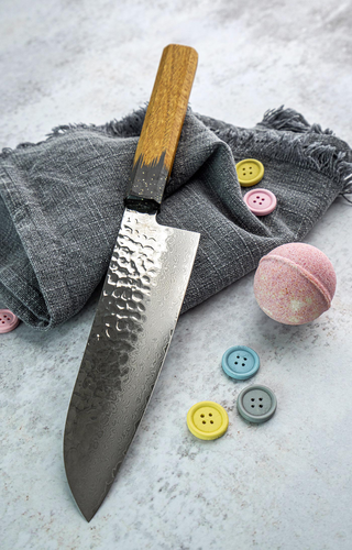 Japoński nóż Santoku Sakai Takayuki Urushi Kokushin na tle szarej tkaniny.