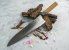 Sakai Takayuki Gyuto Urushi Kokushin nóż 24 cm na tle drewnianych kawałków.