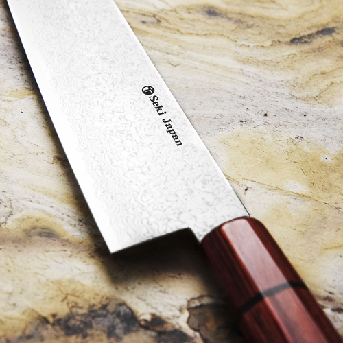 Japoński nóż Santoku Minamo-Kaze Kanetsune na kamiennej powierzchni
