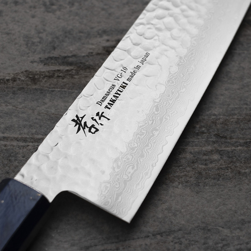 Nóż Gyuto Sakai Takayuki Urushi 24 cm z 33-warstwowej stali VG-10 na tle kamiennego blatu.