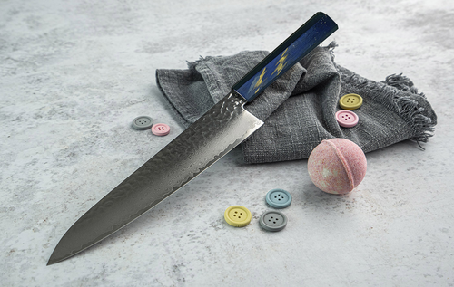 Japoński nóż kucharza Sakai Takayuki Urushi Saiseki 24 cm na tle szarej tkaniny.