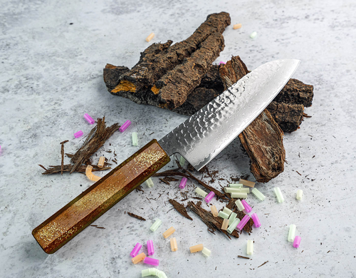 Japoński nóż Santoku Sakai Takayuki Urushi na tle drewna i kolorowych elementów.