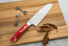Ręcznie kuty nóż Santoku Takeshi Saji na drewnianej desce z kluczami i liśćmi.