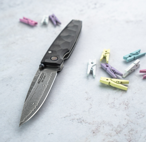 Japoński nóż Mcusta Shinra Emotion 2 Black Pakka Damascus na tle kolorowych spinaczy.