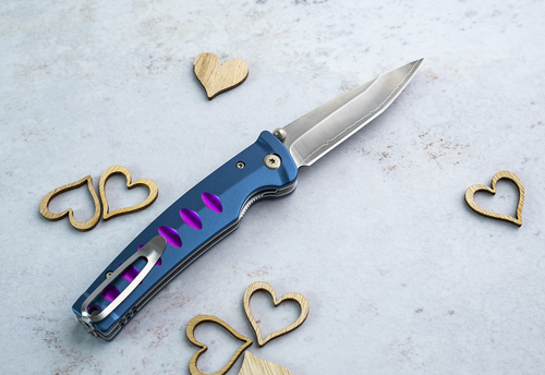 Japoński nóż składany Mcusta Katana Blue-Purple na tle drewnianych serc.