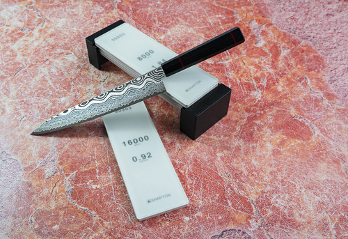 Japoński nóż Kiritsuke Kanetsune Namishibuki 21 cm na tle ostrzałek