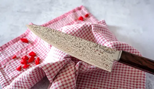 Japoński nóż Santoku Ryoma Rainbow na tle czerwonej ściereczki.