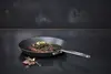 Scanpan Black Iron patelnia z czarnej stali węglowej z soczystym stekiem na ciemnym tle.