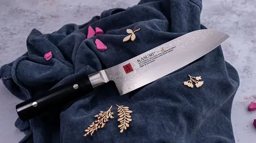 Nóż Santoku Kasumi Masterpiece na tle granatowej tkaniny z dekoracjami