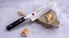 Unikatowy nóż Santoku Kasumi Masterpiece VG-10 GOLD na kamieniu z muszlami.