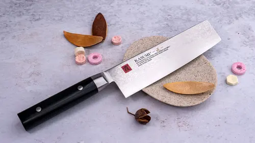 Unikatowy nóż Nakiri Kasumi Masterpiece, 32-warstwowy, VG-10 GOLD, 17 cm, na kamiennej powierzchni.