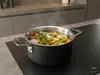 Stalowo-ceramiczny garnek Demeyere Black 5 z zupą warzywną na kuchence.