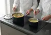 Stalowo-ceramiczny rondel Demeyere Black 5 na kuchence z gotującym się sosem.