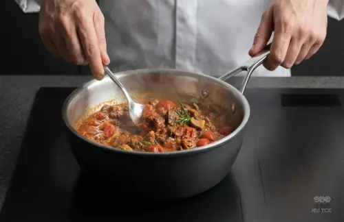 Stalowo-ceramiczna patelnia sauté Demeyere Black 5 z sosem pomidorowym na kuchence.