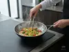 Stalowo-ceramiczny wok Demeyere Black 5 z potrawą w kuchni