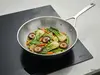Wok Demeyere Black 5 stalowo-ceramiczny z warzywami na patelni.