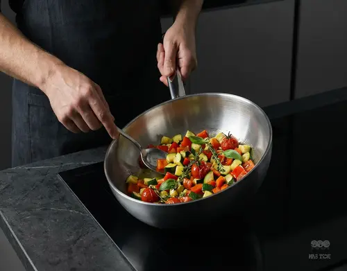 Patelnia sauté Apollo Demeyere z warzywami na kuchence indukcyjnej.