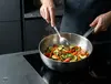 Patelnia sauté Demeyere Apollo stalowa z warzywami na kuchence.
