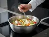 Stalowa patelnia sauté Demeyere Atlantis z warzywami i rybą.