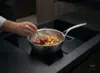 Demeyere Atlantis stalowa patelnia sauté z warzywami na kuchence indukcyjnej